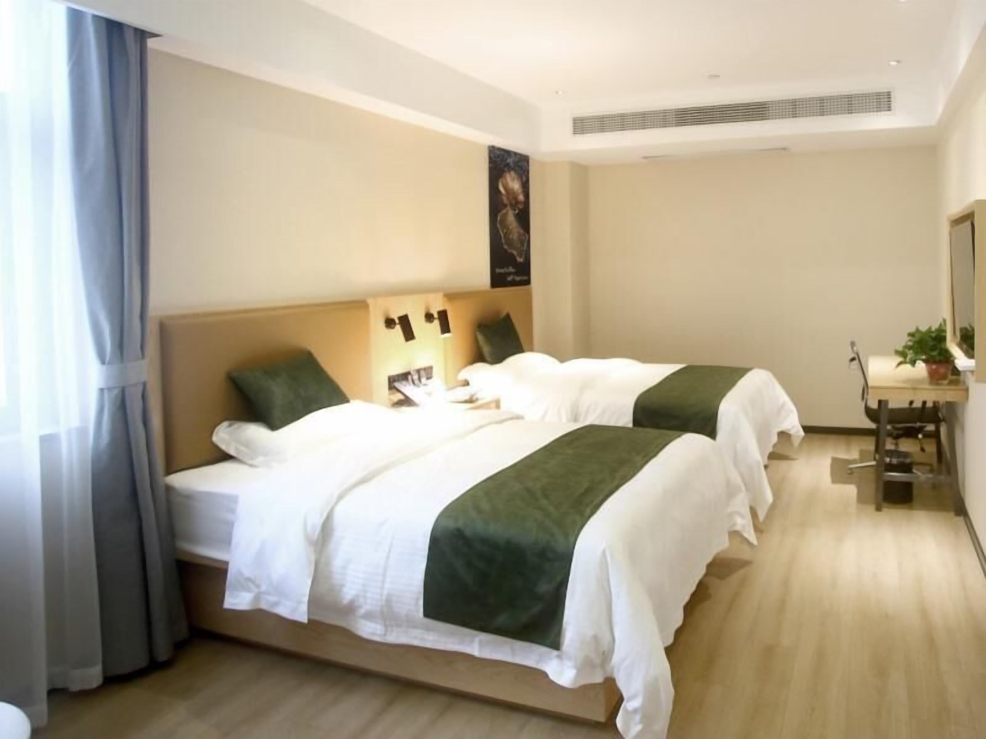 A hotel room with two beds, a desk, and a chair.