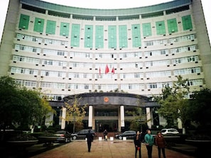 Un edificio de varios pisos con fachada curva, ventanas amplias y una entrada central con una bandera.