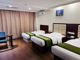 A hotel room with two single beds, a desk, and a chair.