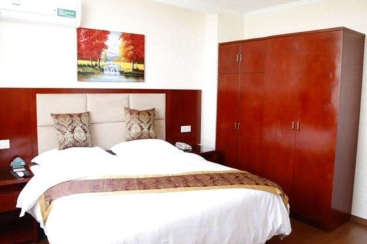 Ein Hotelzimmer mit Bett, Nachttisch, Schrank und einem Bild an der Wand.
