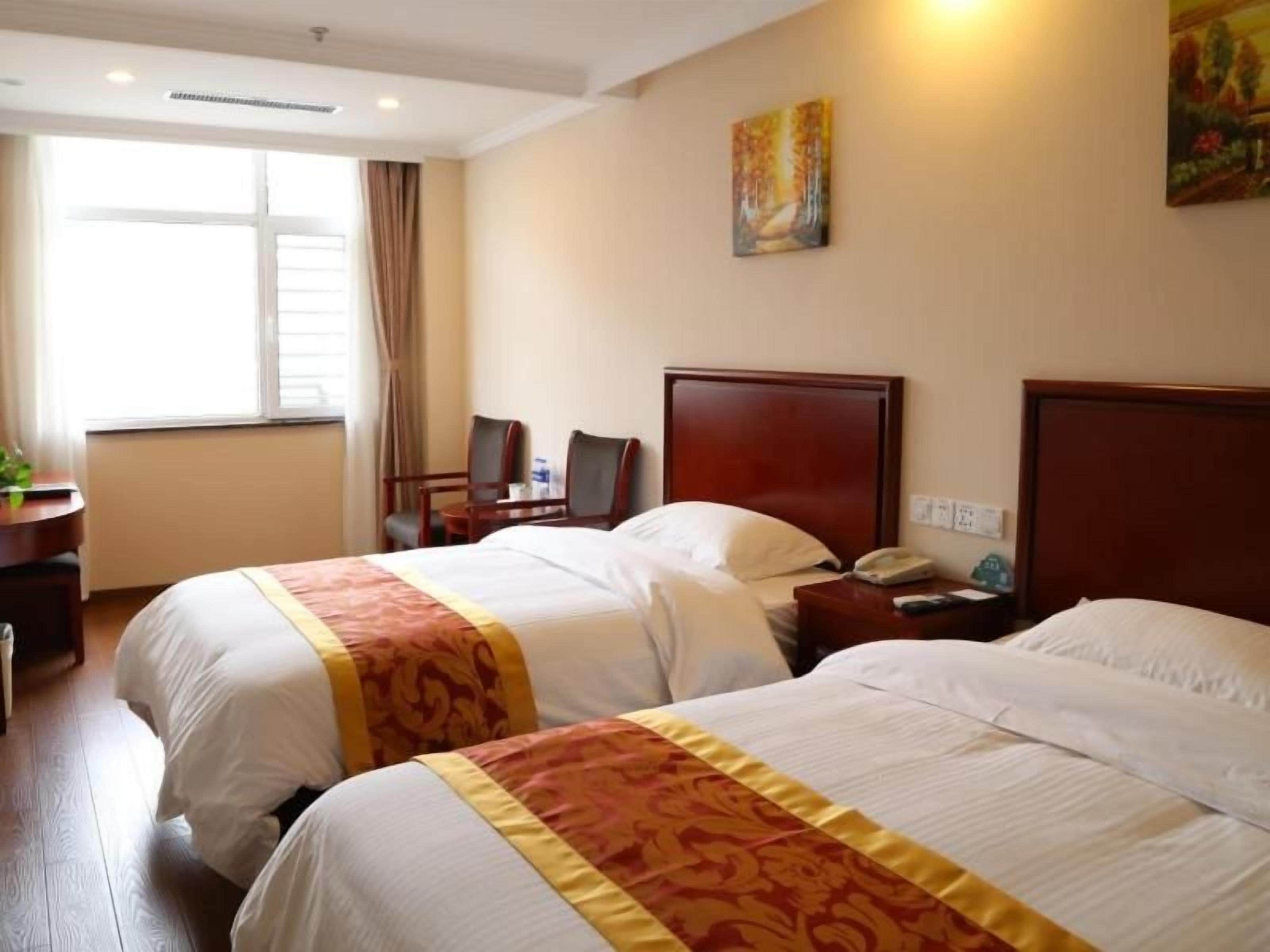 Une chambre d’hôtel avec deux lits, un bureau et une chaise.
