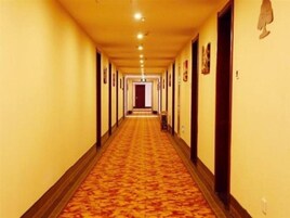 Un pasillo largo y estrecho en un hotel, con alfombra y puertas a ambos lados.