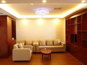 A modern living room with a sofa set, a coffee table, and built-in shelving. - Greentree Inn Heibei Tangshan Nanhujindi Business (Tangshan)