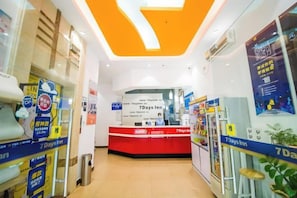 A hotel reception area with a red counter, a sign for 7 Days Inn, and promotional posters on the walls. - 7 Days Inn Jiangmen Qimingli Square Sanshisanxu Street Branch (Jiangmen)