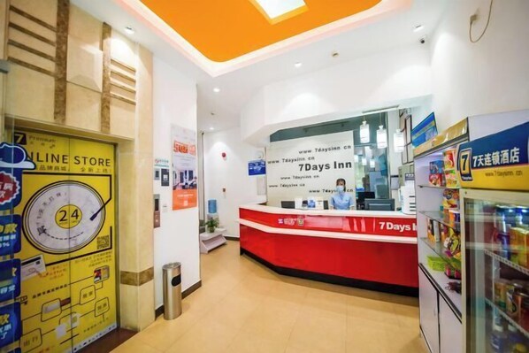 A hotel reception area with a red counter, a 24-hour service sign, and a visible online store sign. - 7 Days Hotel (Jiangmen Qimingli 33 Hui Street Branch) (Jiangmen)