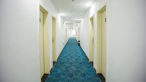 A long, narrow hotel corridor with a blue patterned carpet and white walls. - 7 Days Hotel (Jiangmen Qimingli 33 Hui Street Branch) (Jiangmen)