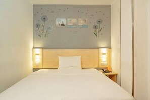 A hotel room with a bed, bedside lamps, a nightstand, and a wall with floral decorations and framed pictures.