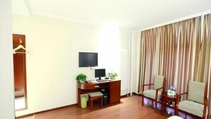 Una habitación con escritorio, dos sillas, televisor y un amplio ventanal con cortinas.