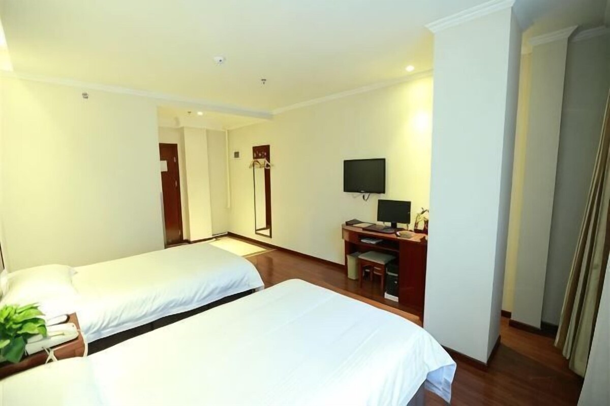 Una habitació d'hotel amb dos llits, un escriptori amb un ordinador, una televisió i un mirall.