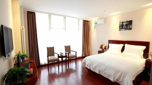 Habitación de hotel con una cama grande, televisión, escritorio con silla y balcón con cortinas.