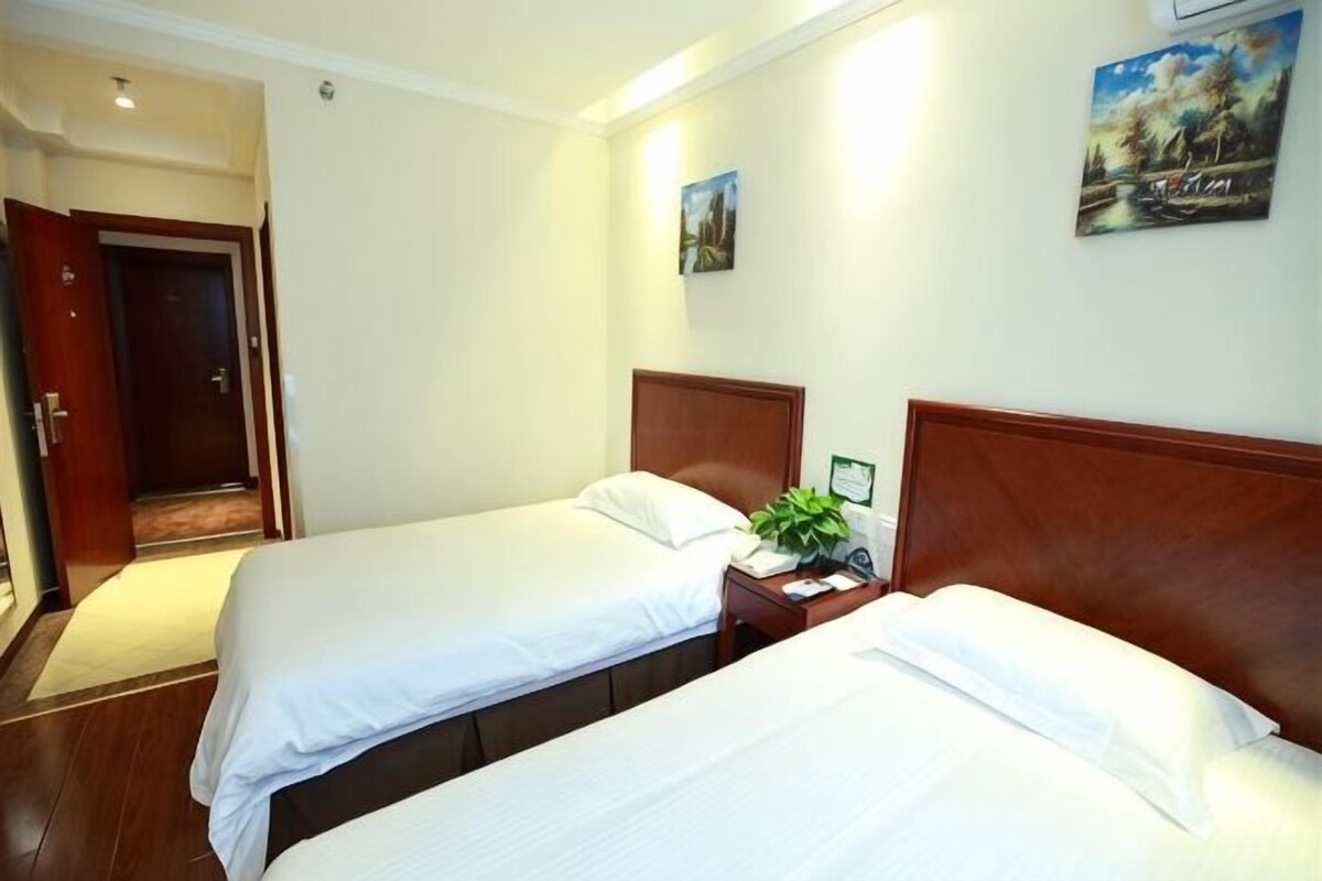 Ein Hotelzimmer mit zwei Betten, einem Holzkopfteil, einem Nachttisch und einem Bild an der Wand.