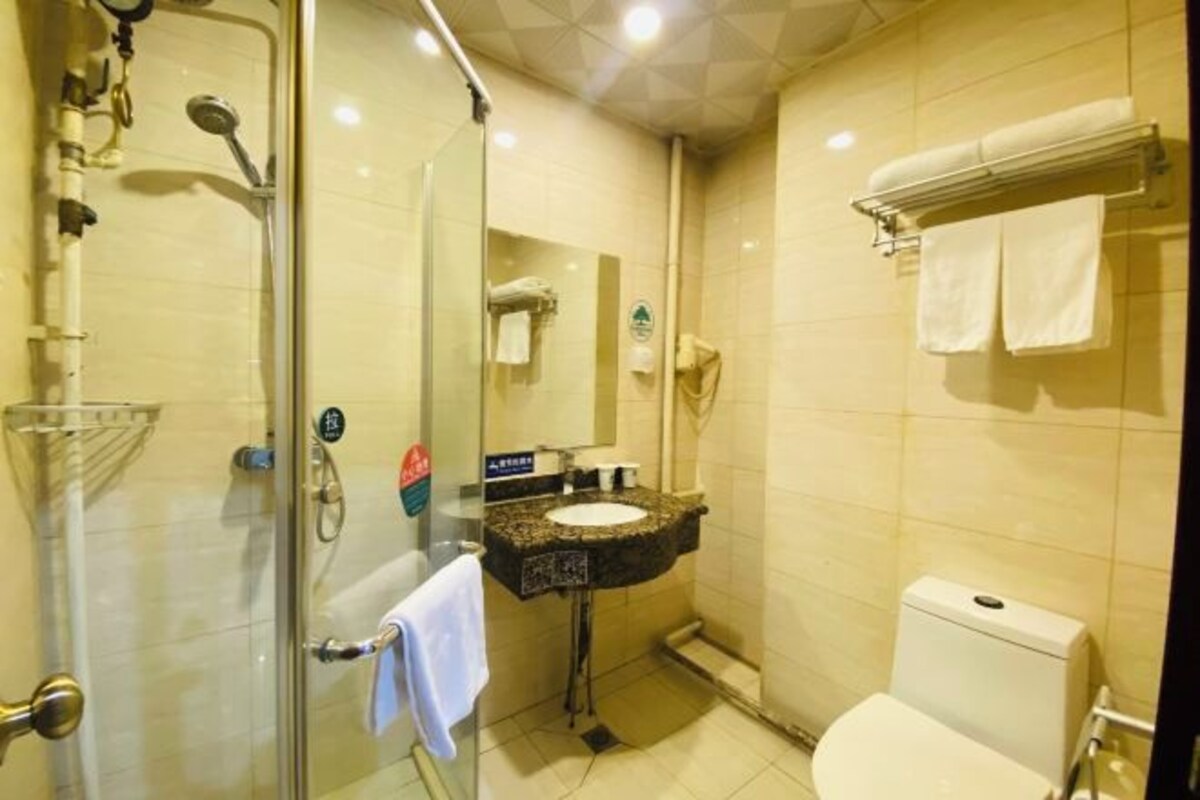 Ein Badezimmer mit Duschkabine aus Glas, Waschbecken mit Spiegel und Toilette.