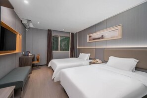 A hotel room with two beds, a desk, a chair, a TV, and a window with curtains.