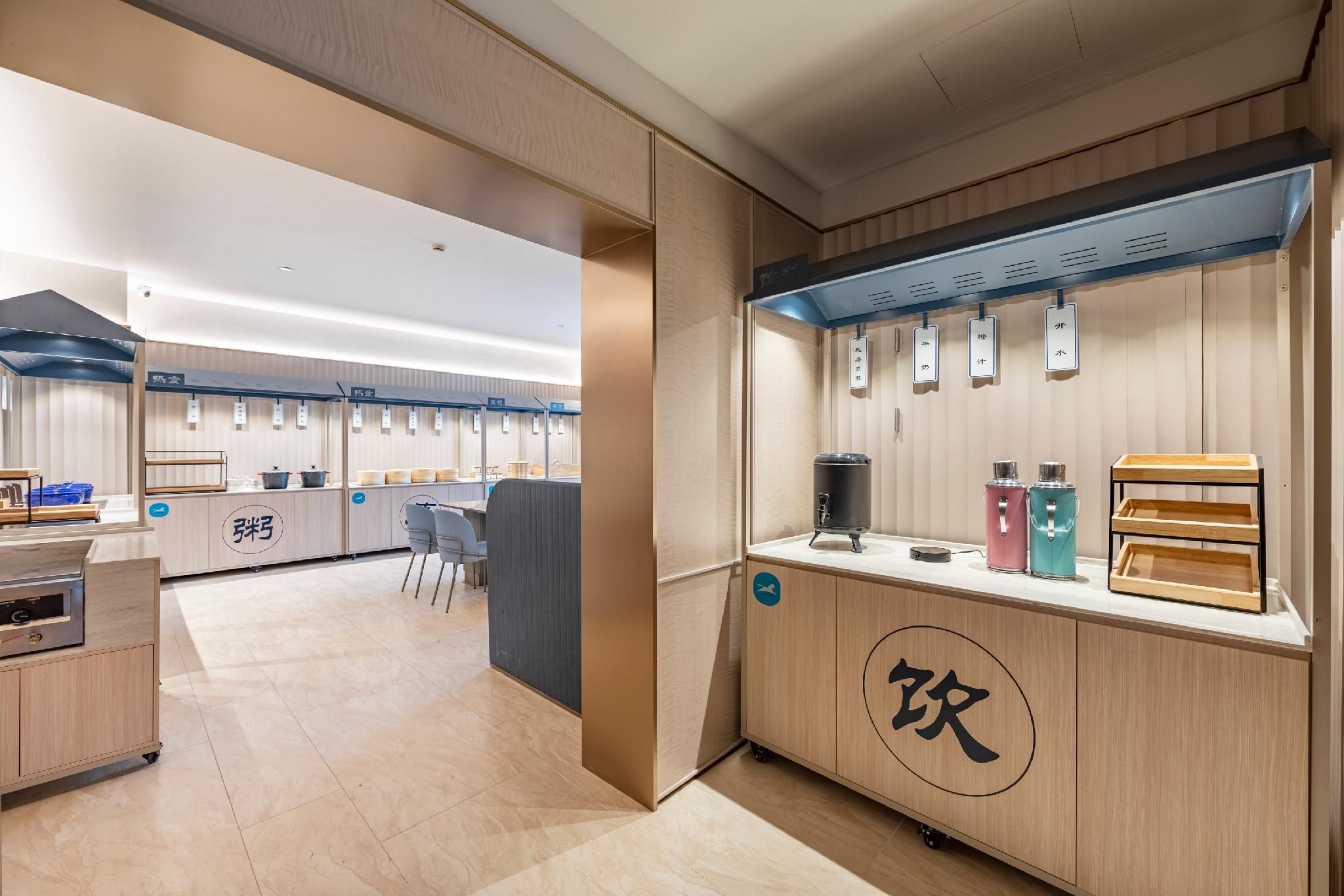A modern kitchen area with a coffee station, seating area, and a counter with various food items.