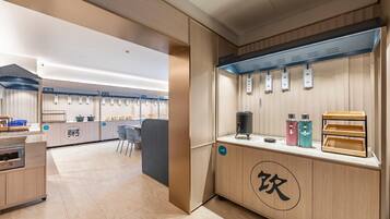 A modern kitchen area with a coffee station, seating area, and a counter with various food items.