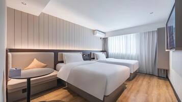 A hotel room with two beds, a sofa, a small table, and a TV.