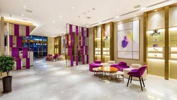 A modern hotel lobby with a reception desk, seating area, and decorative panels.