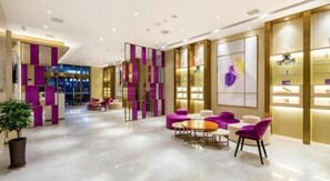 A modern hotel lobby with a reception desk, seating area, and decorative panels.