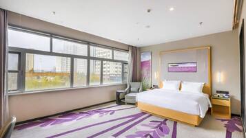 A hotel room with a large window, a bed, a chair, a bedside table, and a wall-mounted TV.