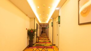 A hotel corridor with a colorful geometric carpet, overhead lighting, and directional signs. - Shell Hefei Economic Development Zone Hk Macao Squ (Hefei)