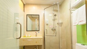 Un baño con cabina de ducha de vidrio, un lavabo con espejo y un inodoro.