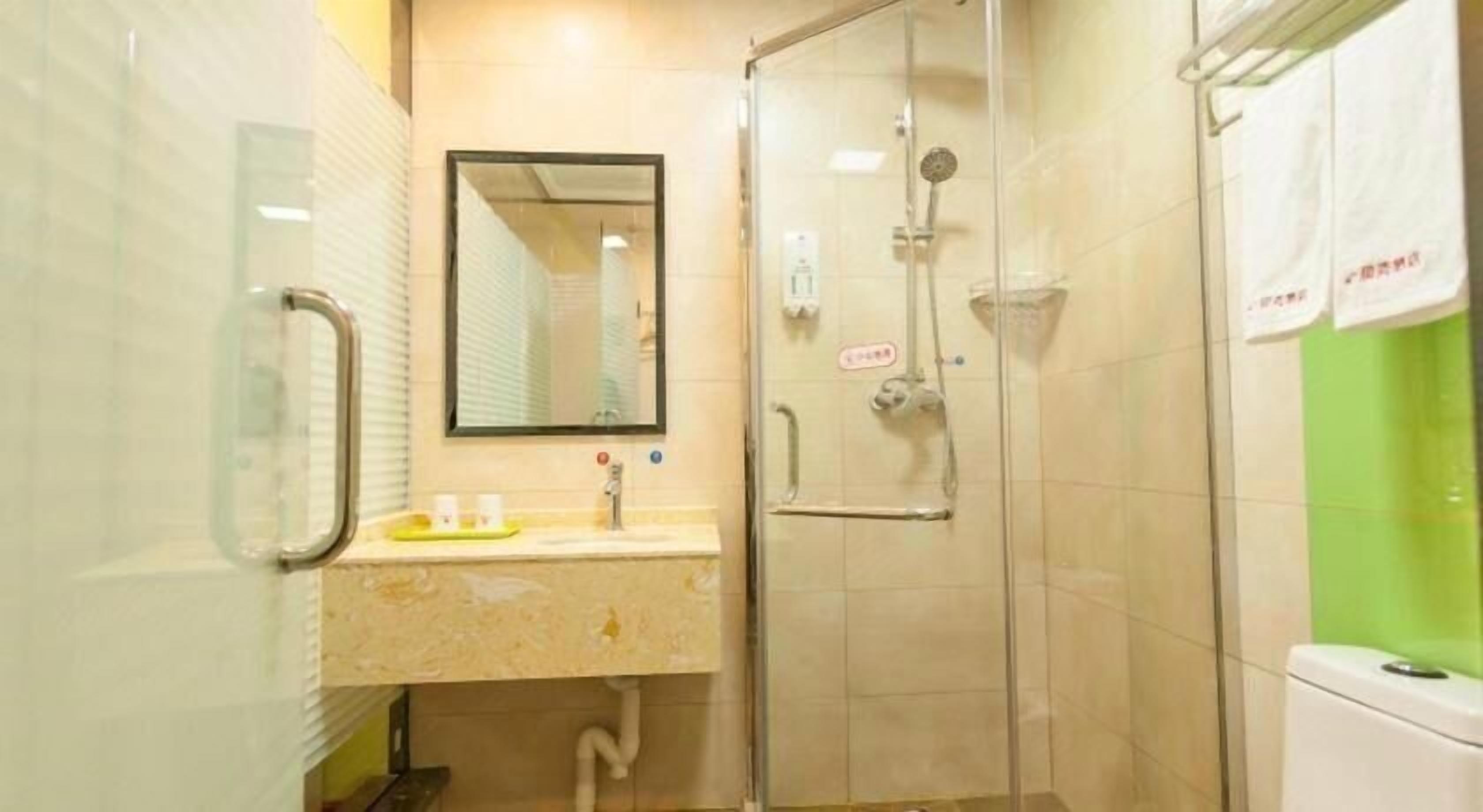A bathroom with a glass shower enclosure, a sink with a mirror above it, and a toilet.