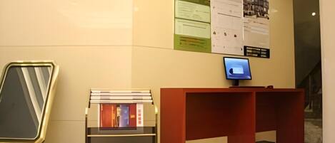 Un mostrador de recepción con un monitor de computadora, una estantería y un espejo.
