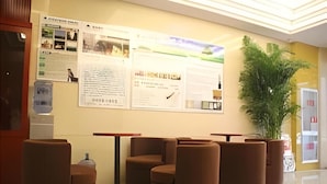 Un hall d'entrée avec des sièges rembourrés de couleur marron, un distributeur d'eau et des affiches d'information accrochées au mur.