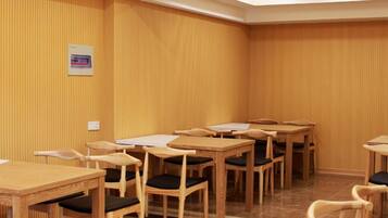A conference room with multiple wooden tables and chairs, a whiteboard, and a small sign on the wall.