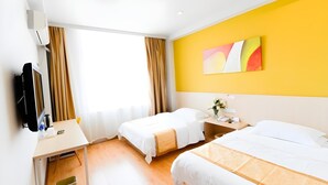 Ein Hotelzimmer mit zwei Betten, einem Schreibtisch, einem Fernseher und einem Fenster mit Vorhängen.