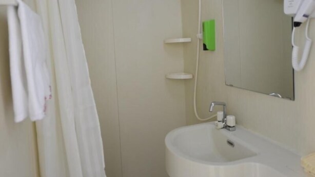 A bathroom with a white sink, a mirror, a shower, and a towel hanging on the wall. - Shell Shengyang Huanggu District The Yalv River Yi (Shenyang)