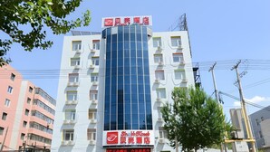 A multi-story building with a prominent glass facade and signage for a business on the ground floor. - Shell Shengyang Huanggu District The Yalv River Yi (Shenyang)