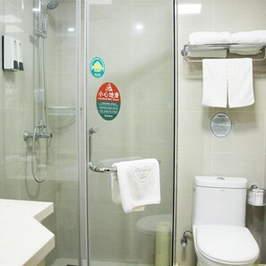 Une salle de bain avec une douche à parois de verre, des toilettes et un porte-serviettes avec des serviettes.