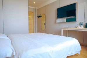 A hotel room with a bed, a TV mounted on the wall, and a desk with a mirror and a few items on it. - Shell Shengyang Huanggu District The Yalv River Yi (Shenyang)