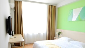 A hotel room with a bed, a desk with a flat-screen TV, a small trash bin, and a window with curtains. - Shell Shengyang Huanggu District The Yalv River Yi (Shenyang)