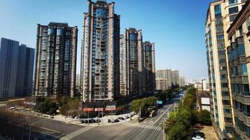 A high-rise residential building with multiple floors, a crosswalk, and a clear sky.