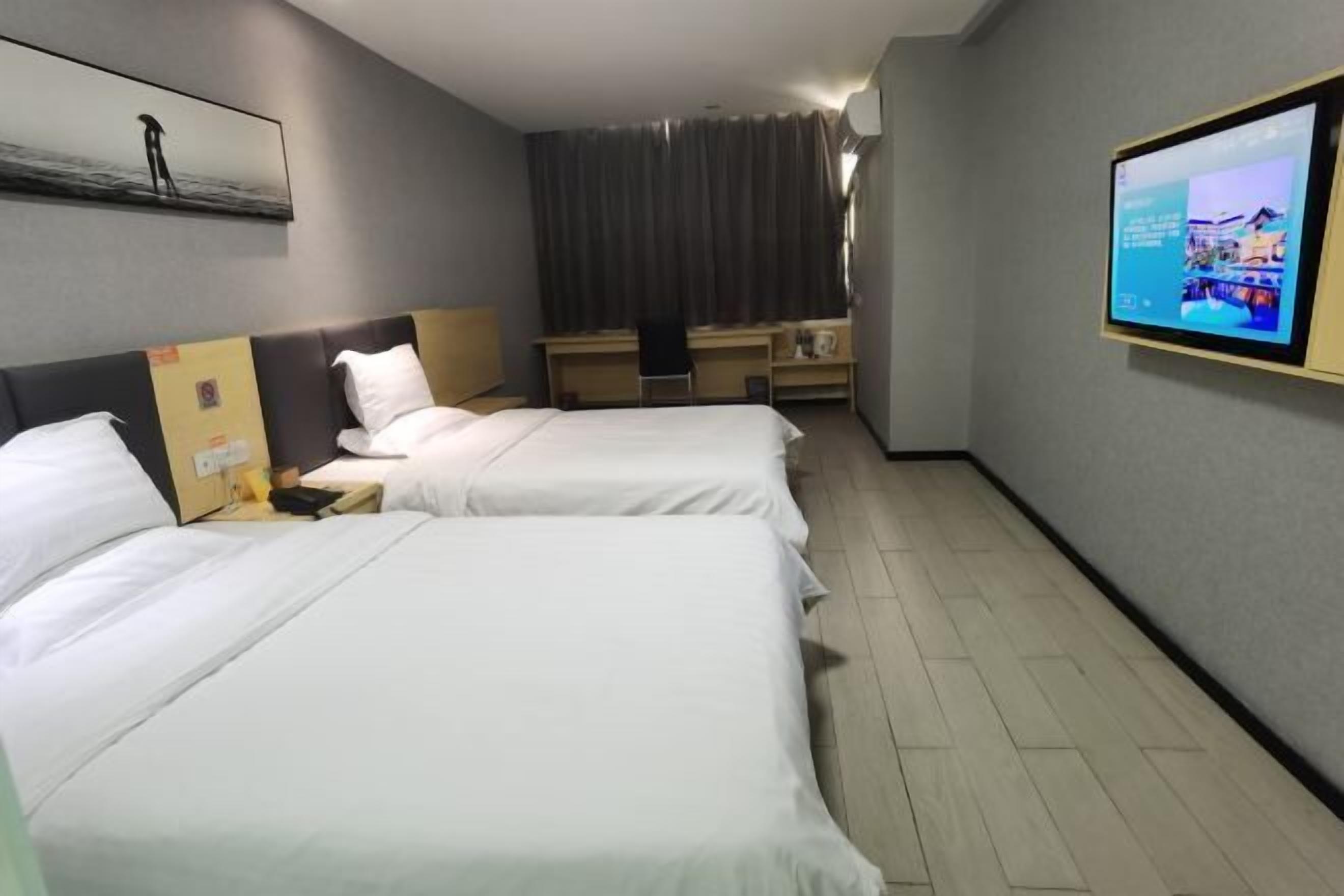 Een hotelkamer met twee bedden, een bureau, een stoel, een televisie en een gordijn.