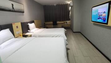 Een hotelkamer met twee bedden, een bureau, een stoel, een televisie en een gordijn.
