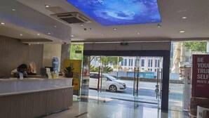 A modern hotel reception area with a glass door leading outside, a digital ceiling display, and a clear view of the street. - Baiyi Hotel (Ji'an Municipal Government Branch) (Ji'an)