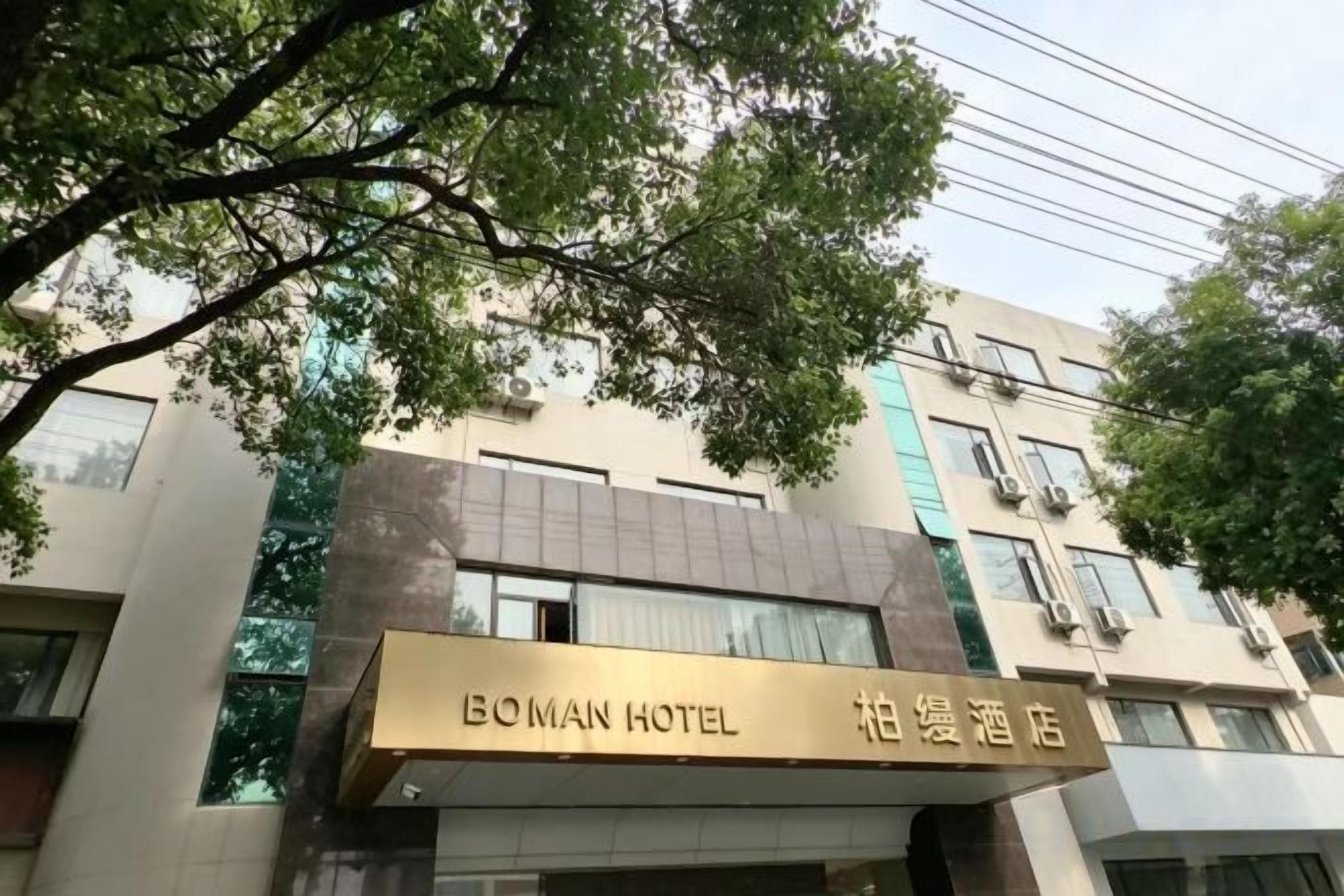 Un hôtel avec une enseigne indiquant « BOMAN HOTEL » et des caractères chinois.