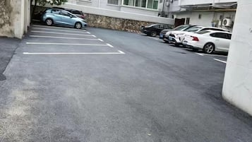 A parking lot with several cars parked, a building with a stone facade, and a clear sky.