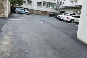A parking lot with several cars parked, a building with a stone facade, and a clear sky. - Baiyi Hotel (Ji'an Municipal Government Branch) (Ji'an)