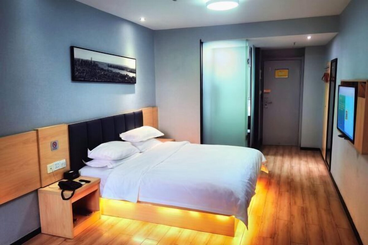 Une chambre d’hôtel équipée d’un lit, d’une table de chevet et d’un téléviseur fixé au mur.