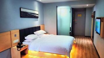 A hotel room with a bed, bedside table, and a wall-mounted TV.