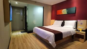 A hotel room with a bed, a desk, a chair, a TV, and a painting on the wall.