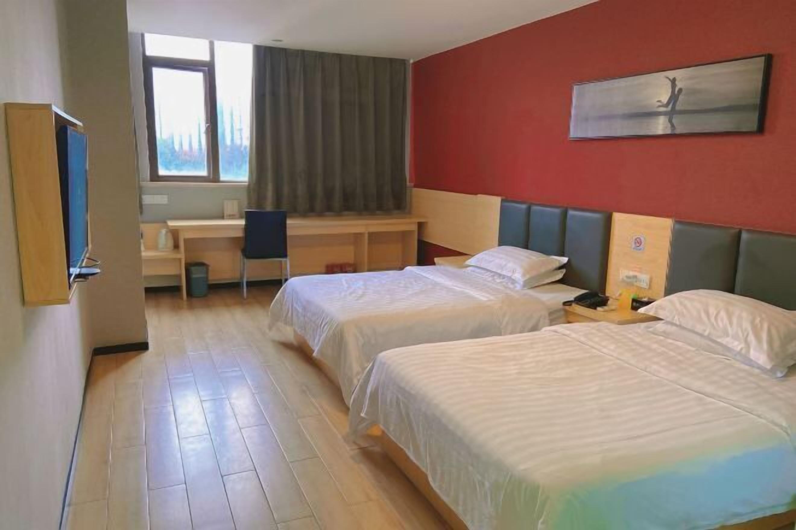 Een hotelkamer met twee bedden, een bureau en een groot raam.
