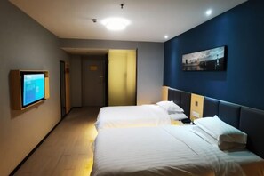Une chambre d’hôtel avec deux lits, une télévision, un tableau au mur et un couloir.