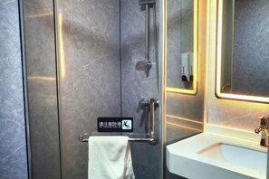 Une salle de bain équipée d’une barre d’appui, d’un porte-serviettes, d’un lavabo et d’un miroir.