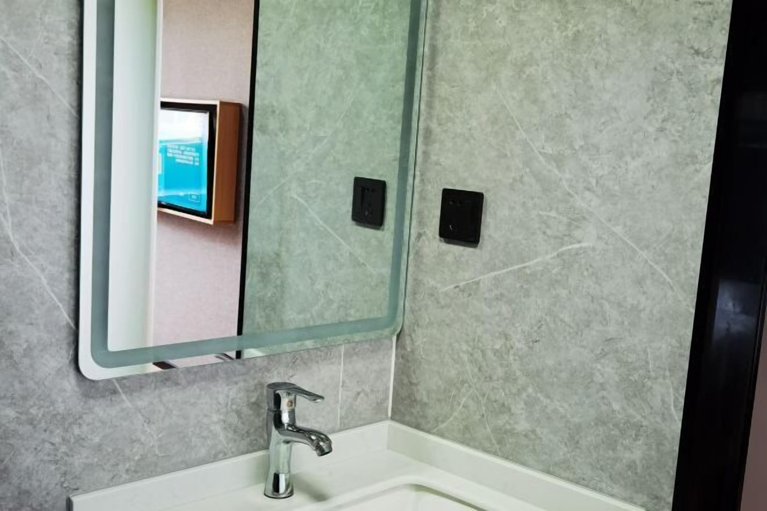 Une salle de bain avec un miroir, un lavabo et des murs carrelés.