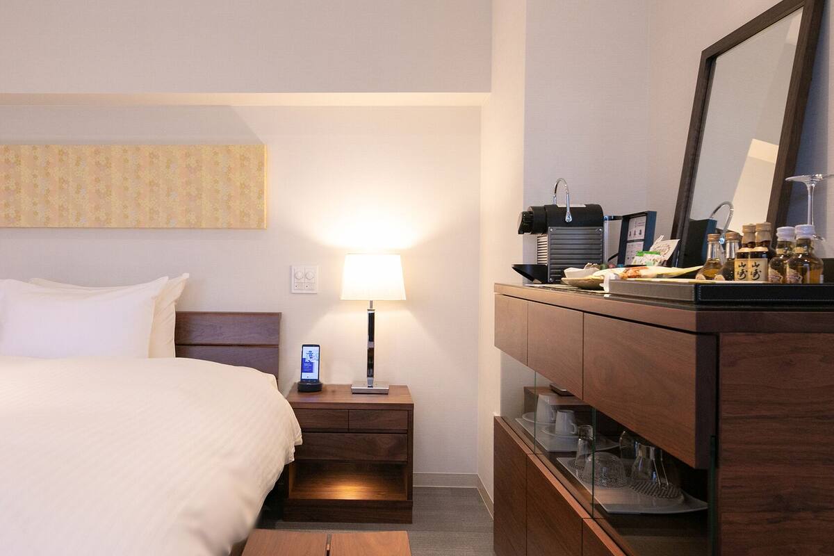 Une chambre d’hôtel équipée d’un lit, d’une table de chevet, d’une lampe et d’un mini-bar.